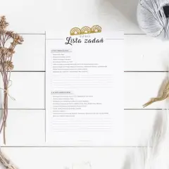 Lista zadań do zrobienia przed ślubem, z zaznaczonymi punktami. Obok leży gałązka suszonych kwiatów i złote nożyczki.