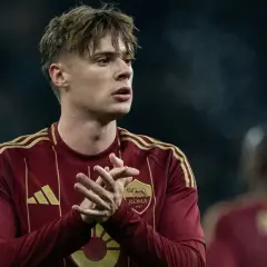 Piłkarz Nicola Zalewski w bordowej koszulce AS Roma z żółtymi pasami na ramionach.