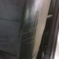 Siège de voiture en cuir noir avec des éraflures visibles, nécessitant une réparation de griffure cuir.