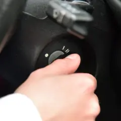 Dłoń przekręca kluczyk w stacyjce samochodu.