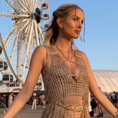 Una ragazza con glitter sul viso e un abito dorato, sullo sfondo la ruota panoramica e la folla: ecco cos'è il Coachella, un festival di musica e moda.