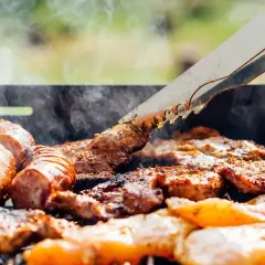Des saucisses et des morceaux de viande au barbecue, fumants et grillés à la perfection. Un délice estival.