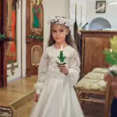 Dziewczynka w białej sukni i wianku trzyma świecę. To ważny dzień, w której klasie komunia?