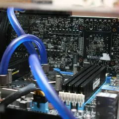 Composants d'un PC, dont des tubes bleus de watercooling et des barrettes de RAM. Utile pour connaître sa carte mère Windows 10.