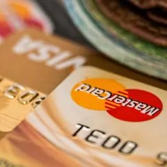 Zbliżenie na karty płatnicze Visa i Mastercard, z widocznym numerem karty i logo. Może to oznaczać debet na karcie lub po prostu jej posiadanie.