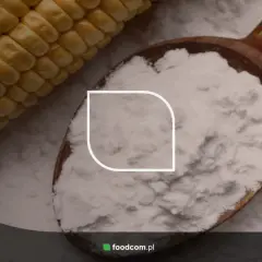 Łyżka pełna białego proszku, prawdopodobnie skrobia modyfikowana, obok kolby kukurydzy.