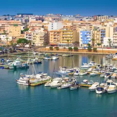 Puerto deportivo con muchos barcos y edificios de colores. Descubre qué hacer en Roquetas de Mar.