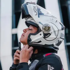 Mujer ajustando su casco integral o modular, listo para la aventura.