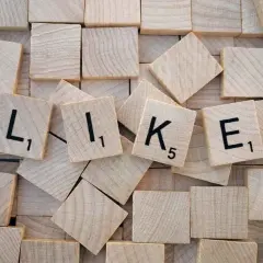 Wooden tiles spelling out "LIKE" with black letters and numbers.