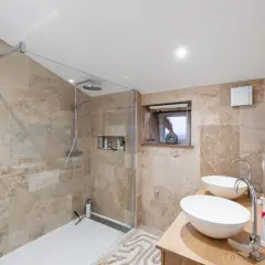 Salle de bain moderne aux tons sable, avec douche à l'italienne, double vasque et dressing attenant. Un exemple de travaux rénovation salle de bain réussis.