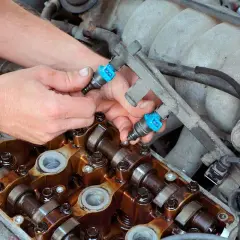 Mecánico instala inyectores de combustible en un motor. Aunque se puede circular con un inyector averiado, es mejor repararlo.