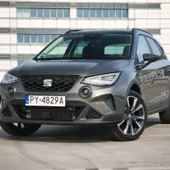 Szary Seat Arona 1.0 TSI zaparkowany przed nowoczesnym budynkiem.