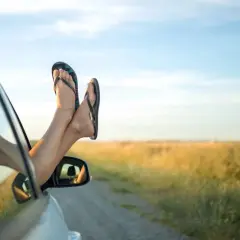 Pieds en claquettes sortant de la fenêtre d'une voiture, profitant du voyage par une journée ensoleillée.