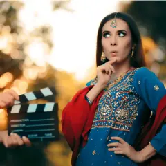 Kobieta w tradycyjnym indyjskim stroju i klaps filmowy na planie.