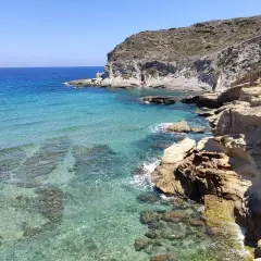 Aguas cristalinas y rocas escarpadas en la playa del embarcadero. Un lugar idílico para disfrutar del sol y el mar.