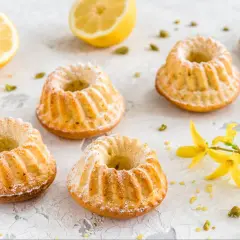 Szybkie babeczki wielkanocne, oprószone cukrem pudrem, z cytryną i pistacjami w tle.