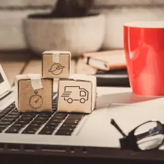 Miniaturki paczek z ikonami transportu na klawiaturze laptopa. Zastanawiasz się, ile zarabia spedytor?