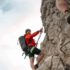 Frau klettert gesichert einen Felsgrat entlang, ein Abenteuer auf den Klettersteigen Bayerns.