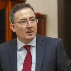 Poseł Bartłomiej Sienkiewicz w garniturze i czerwonym krawacie, w okularach, patrzy w bok.