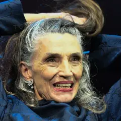 Mujer con peinados pelo largo liso, plateado y castaño, sonriendo y tocándose el cabello con las manos.