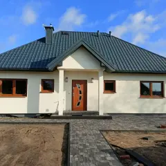 Nowoczesne domki kanadyjskie całoroczne pod klucz. Jasna elewacja, ciemny dach, drewniane okna i drzwi.