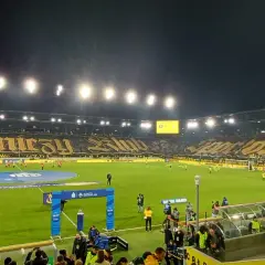 Piłkarze GKS Katowice i Górnika Zabrze na murawie. Na trybunach ogromna oprawa z napisem "Górniczy Klub".