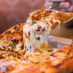 Rozciągający się ser na kawałku domowej pizzy.
