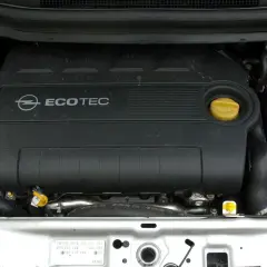 Silnik Ecotec w Oplu Zafira B. Widoczny czarny plastikowy dekiel z logo Opla i napisem Ecotec, żółty korek oleju i zbiorniczek płynu chłodniczego.