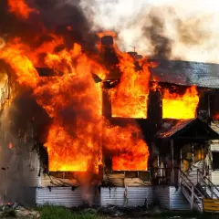 Ein Haus brennt lichterloh. Die Flammen schlagen aus den Fenstern. Hoffnung auf finanzielle Hilfe nach Brand ohne Versicherung.