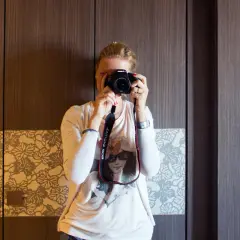 Dziewczyna z aparatem w rękach, ćwiczy na zajęciach szkoły fotografii.