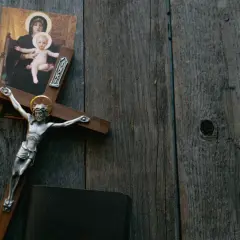 Krzyż z Jezusem, obraz Matki Boskiej i Biblia na drewnianym tle. Symbolika odkupienia i wiecznej kary za grzechy.