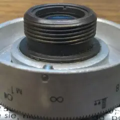 Metalowy pierścień z oznaczeniami od 1 do 8, nieskończoności i innymi symbolami, służący do regulacji obiektywu. Idealny do zoom test.