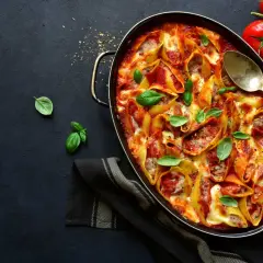 Conchiglioni farcis à la sauce tomate et au fromage, prêts à faire lever la pâte au four. Garnis de basilic frais.