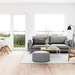 Elegante salón comedor con sofás grises, mesa de madera y sillas blancas. La iluminación se logra con lámparas colgantes y de pie, perfectas para combinar lamparas salon comedor.