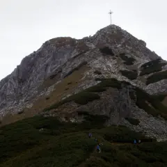 Wspinaczka na Giewont, gdzie w trudnym terenie pomagają łańcuchy. Widok na szczyt z krzyżem.