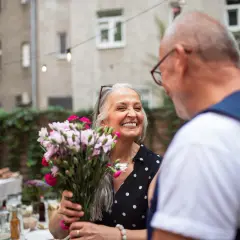 Uśmiechnięta kobieta z bukietem kwiatów, słysząca wzruszające cytaty: "Dziękuję, że jesteś".