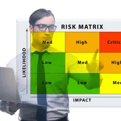 Uomo con laptop davanti a una matrice dei rischi, da cosa possiamo evincere il rischio dell'attività lavorativa.