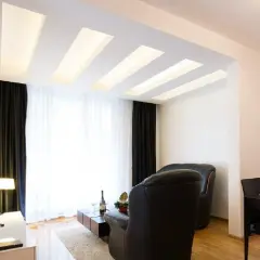 Nowoczesny salon z designerskim plafonem led, który subtelnie rozświetla wnętrze. Drewniane elementy dodają ciepła.