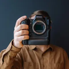 Osoba trzyma aparat Nikon Z9, zasłaniając twarz. Trwa test tego profesjonalnego sprzętu.
