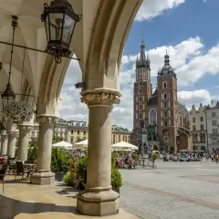 Podcienia Sukiennic w Krakowie, z widokiem na Rynek Główny i Kościół Mariacki. Stare miasto kraków tętni życiem.