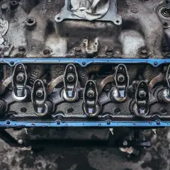 Detalle de balancines y resortes de un motor, con aceite visible, parte del sistema de lubricación.