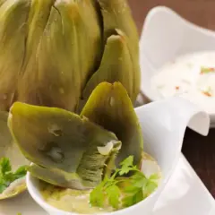 Alcachofas enteras cocidas, servidas con salsas para mojar. Una delicia para disfrutar.