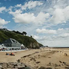 Plage normande avec restaurant en bord de mer, gens sur le sable et terrain de volley.