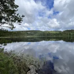 Spegelblank sjö med moln som reflekteras. Perfekt för en paus under cykelturen på cykelleder Sverige.