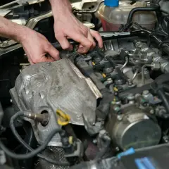 Mechanik pracuje przy silniku, szukając czujnika położenia wałka rozrządu.