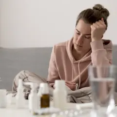 Zmęczona kobieta z lekami na stole. Czy to niedobór ferrytyny?