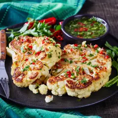 Idealny pomysł na kalafiora na obiad: pieczone steki z kalafiora z sosem chimichurri, posypane chili i pietruszką.
