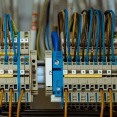 Starannie wykonane przyłącze elektryczne z wieloma przewodami w różnych kolorach, podłączonymi do zacisków.