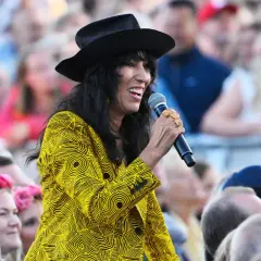 Titiyo, med sitt karakteristiska gula mönstrade plagg och svarta hatt, sjunger för en stor publik. Hon ser ut att ha roligt, precis som ett glatt titiyo barn.