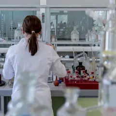 Naukowczyni w białym fartuchu pracuje w laboratorium, otoczona szkłem laboratoryjnym. Analizuje próbki, być może badając rdw-cv.